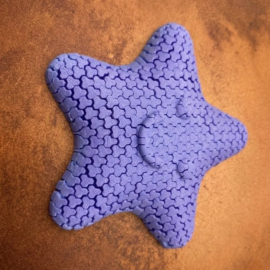 Estrella flexible impresa en PLA lila, formada por eslabones entrelazados y con carita sonriente