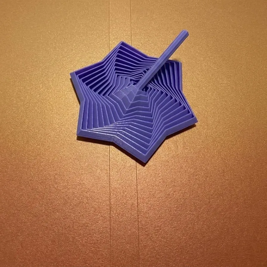Trompo en espiral con forma de estrella, impreso en PLA lila y visto desde arriba
